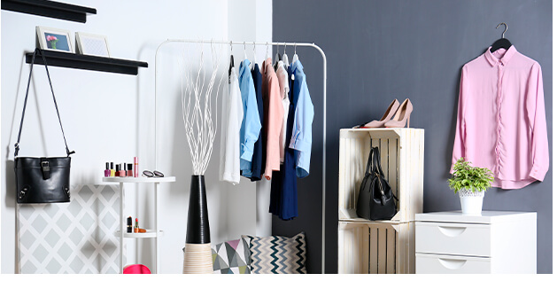 Corner of bedroom with open shelving containing clothing accessories and make up as well as a garment clothing rack